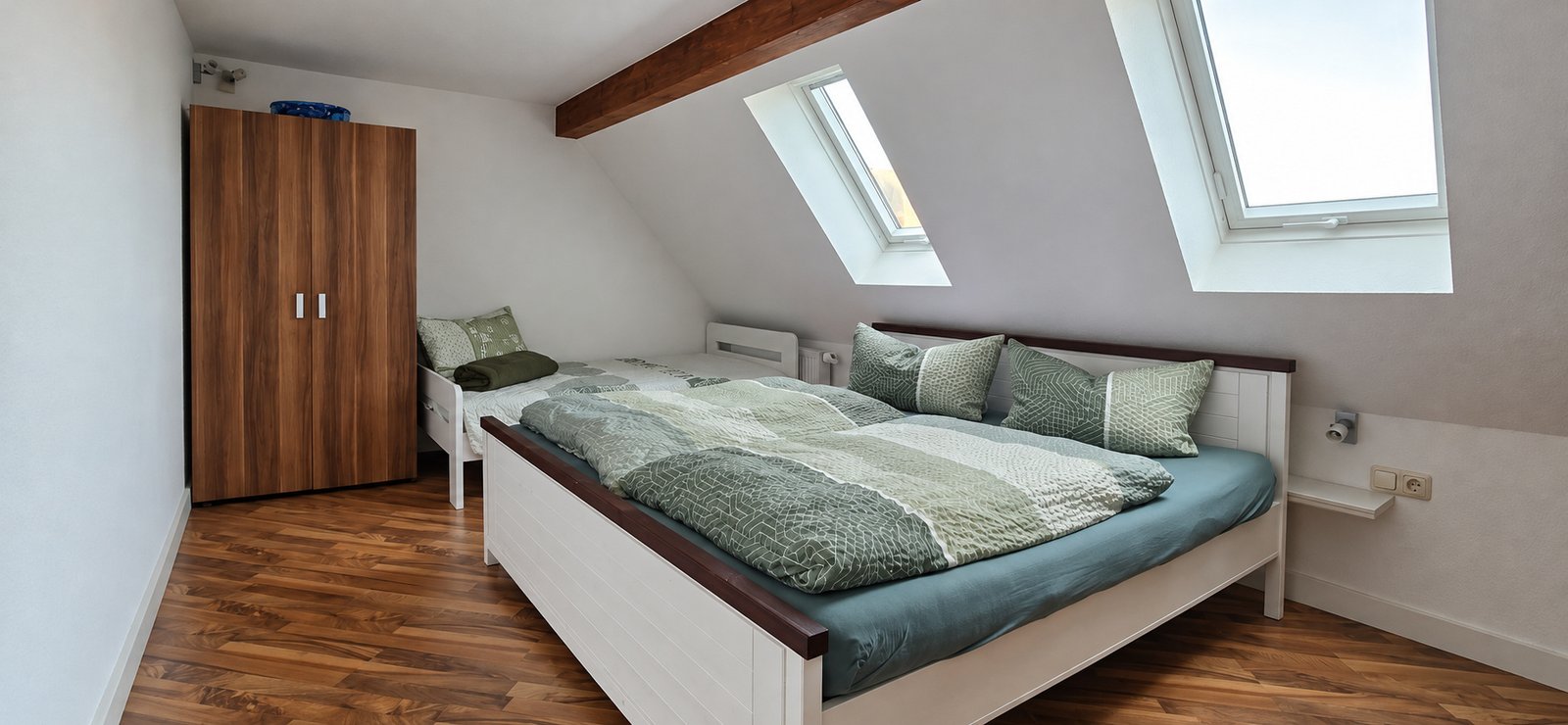 Schlafzimmer im Obergeschoss mit Doppelbett, Einzelbett und Dachfenstern