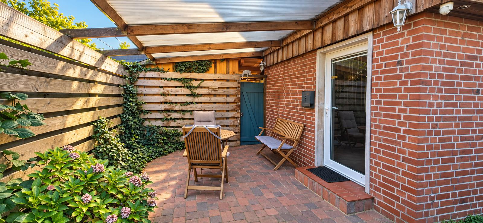 Überdachte Terrasse mit Gartenmöbeln, Sichtschutz und Hortensien